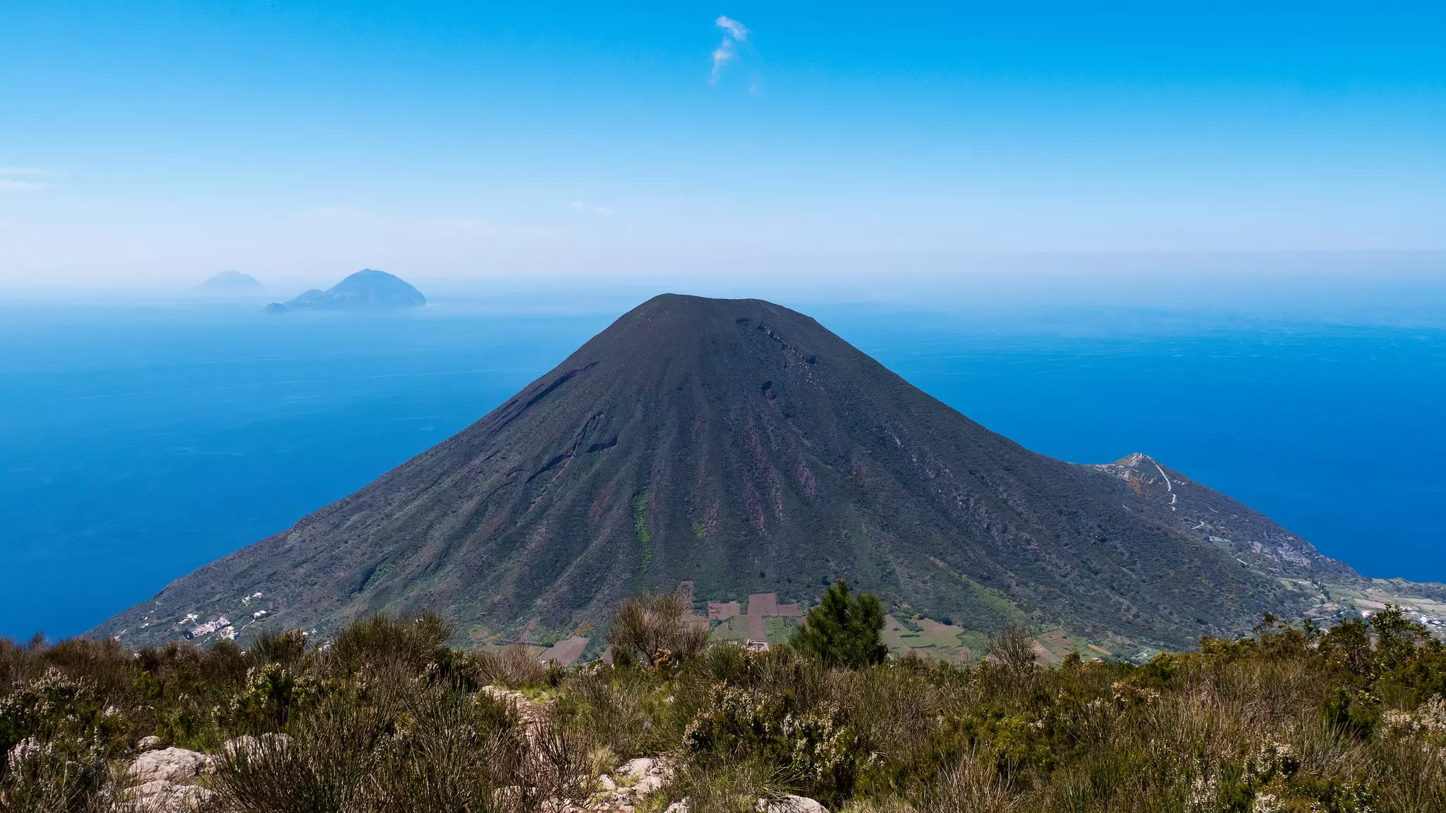 A stratovolcano is pictured, with the sea and other islands beyond.