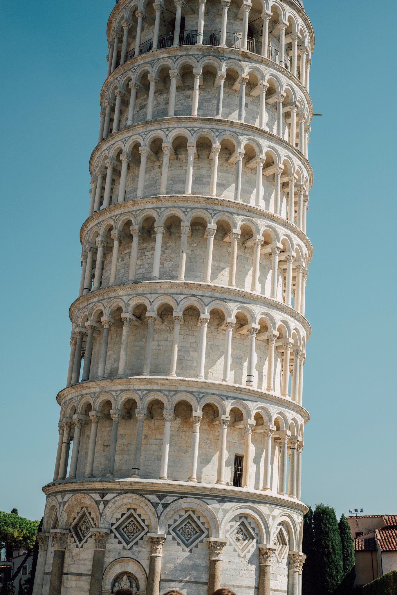 Close-up of the Leaning Tower of Pisa against the light blue backdrop of the sky.