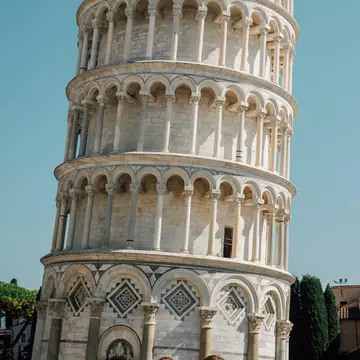 Close-up of the Leaning Tower of Pisa against the light blue backdrop of the sky.