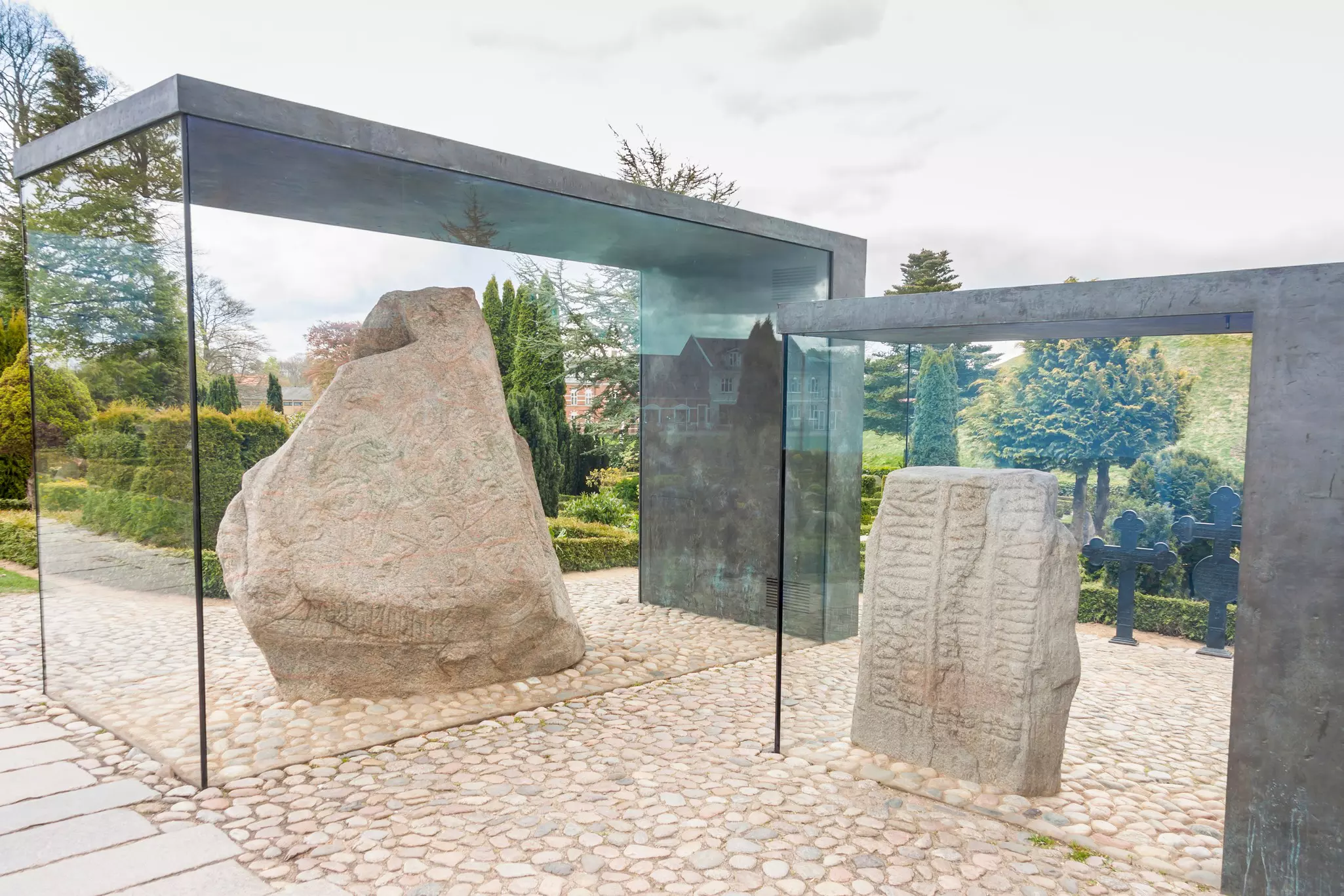Two large stones carved with runes are enclosed in an outdoor display.