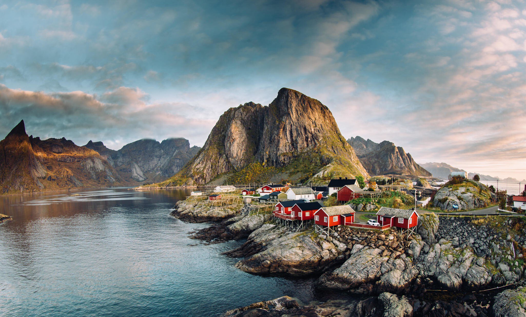 Norwegian fishing village of Hamnoy in the Lofoten Islands. Dramatic sunset clouds above steep mountain peaks.