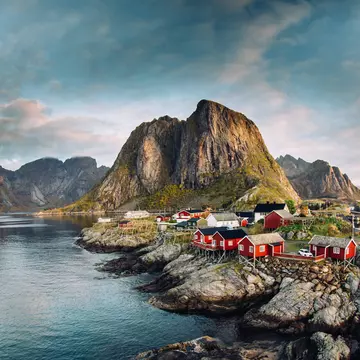 Norwegian fishing village of Hamnoy in the Lofoten Islands. Dramatic sunset clouds above steep mountain peaks.