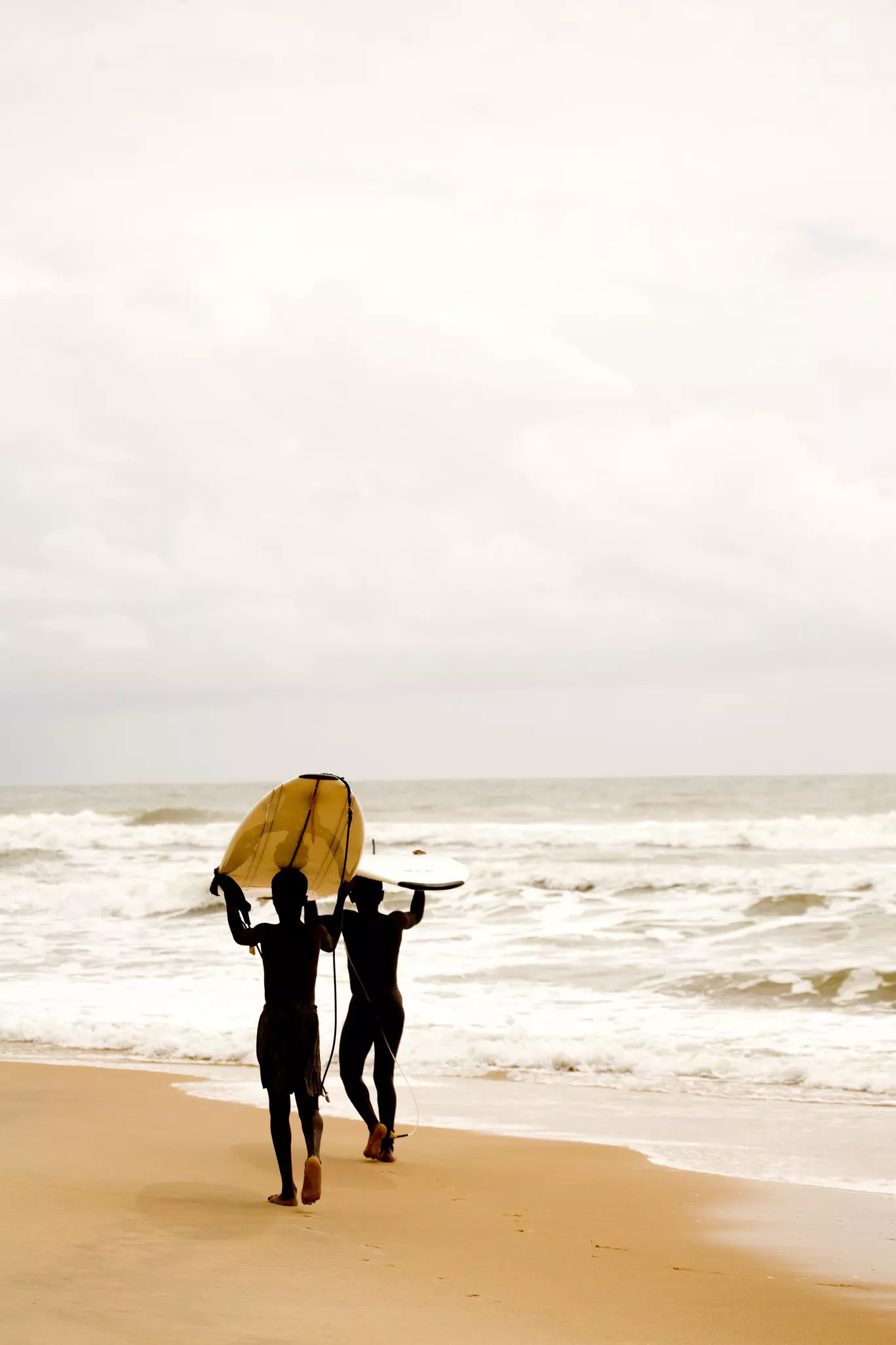 Liberia, Cape Mount, Robertsport, surfer walking on the beach