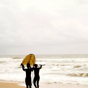 Liberia, Cape Mount, Robertsport, surfer walking on the beach