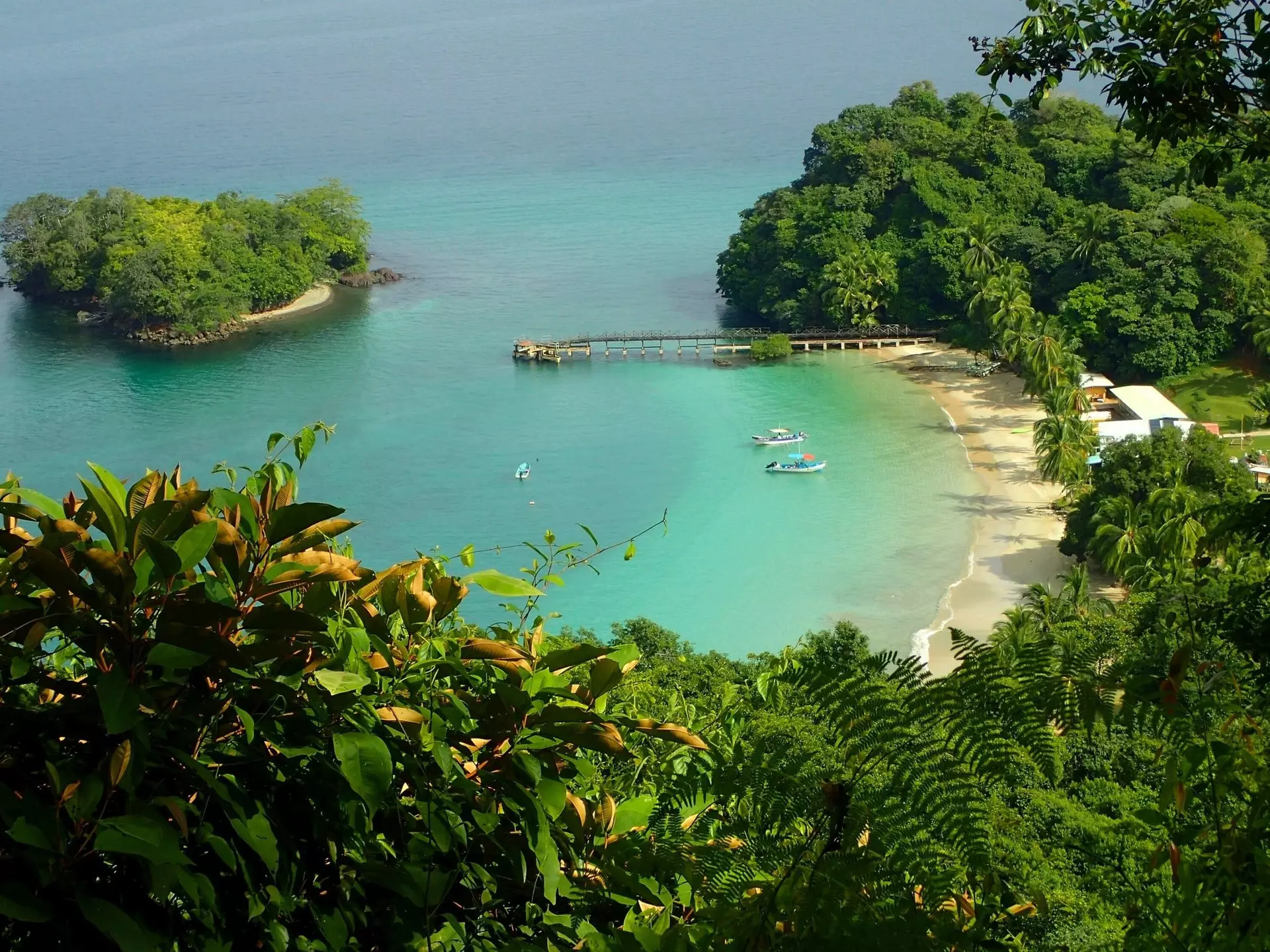 Jungle-backed beach. A few small boats are moored near the sandy cove in Coiba National Park, Panama