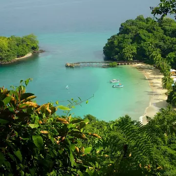 Jungle-backed beach. A few small boats are moored near the sandy cove in Coiba National Park, Panama