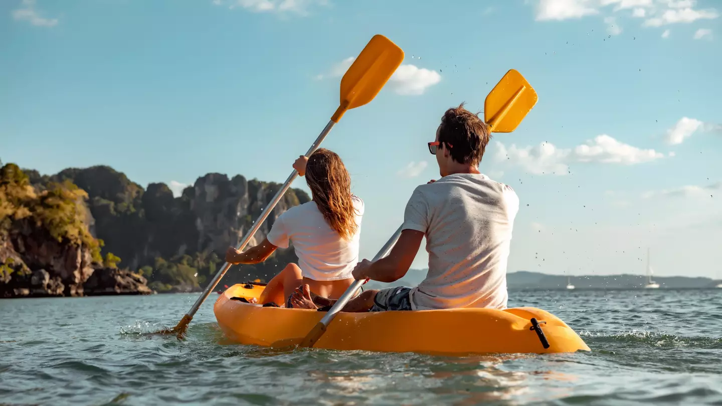 Sea kayaking or canoeing concept with young couple kayakers at tropical bay.