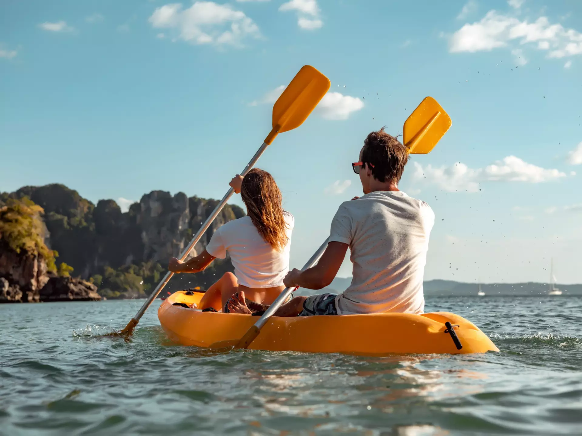 Sea kayaking or canoeing concept with young couple kayakers at tropical bay.