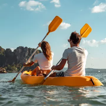 Sea kayaking or canoeing concept with young couple kayakers at tropical bay.