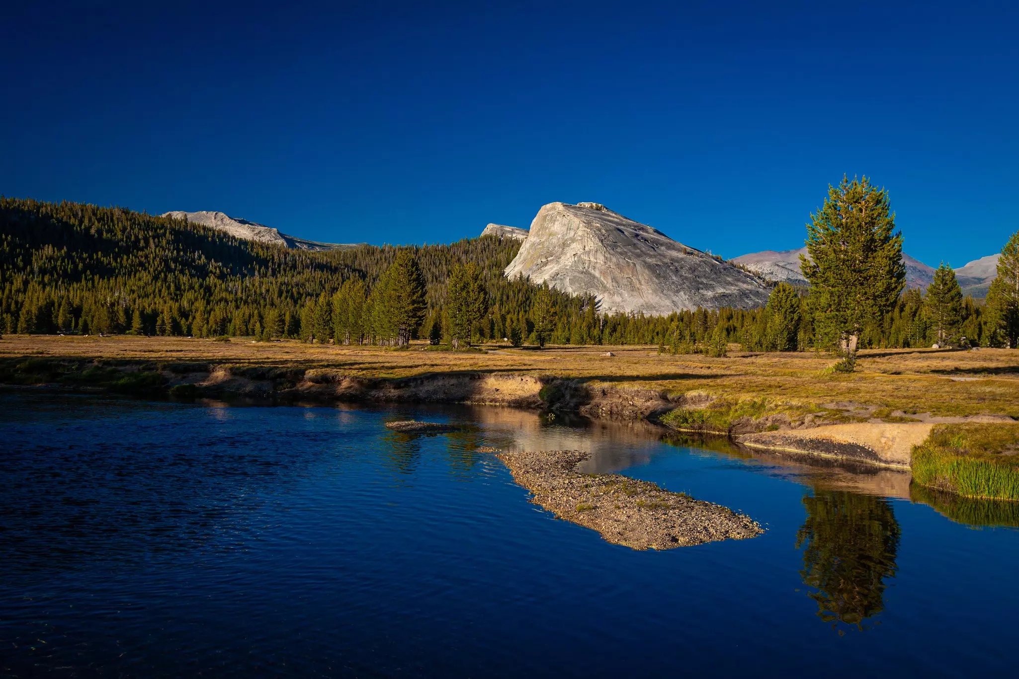 Two campers sit near a river in Yosemite National Park, California