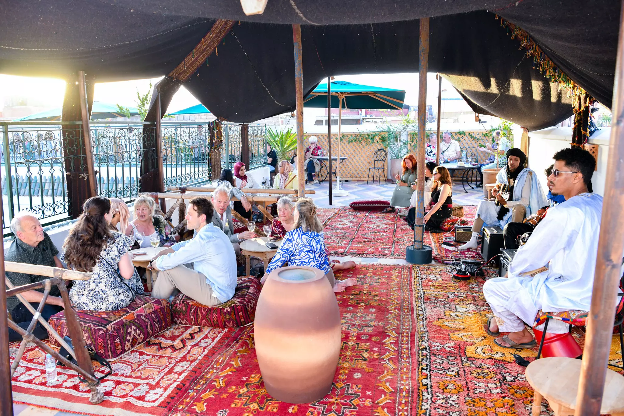 People sit at tables on a red patterned carpet.
