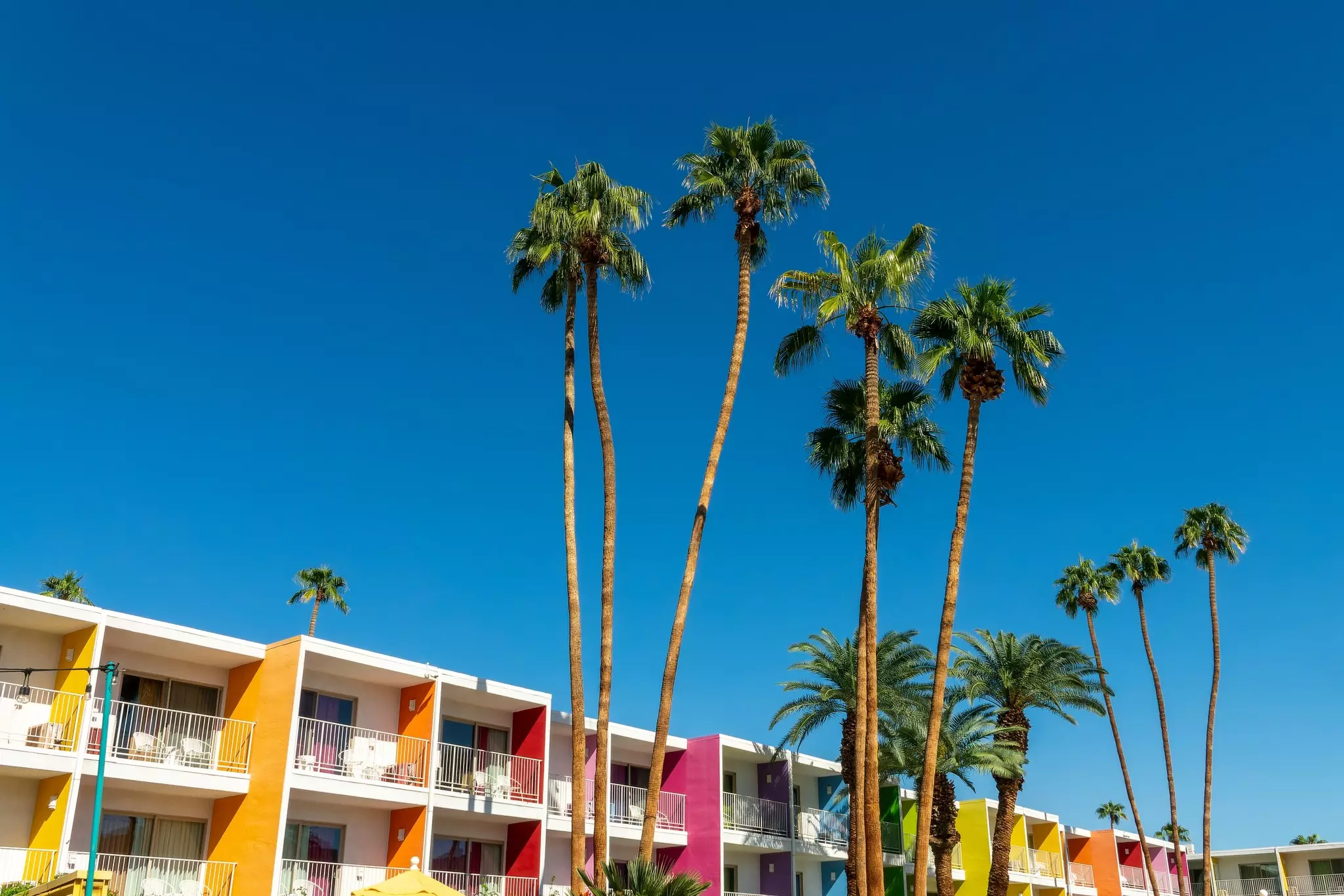 A hotel complex with multicolored panels and palm trees.