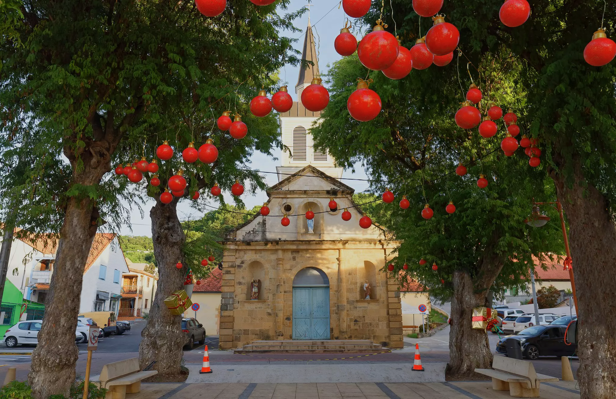 Trees covered in red Christmas ornaments in front of a church