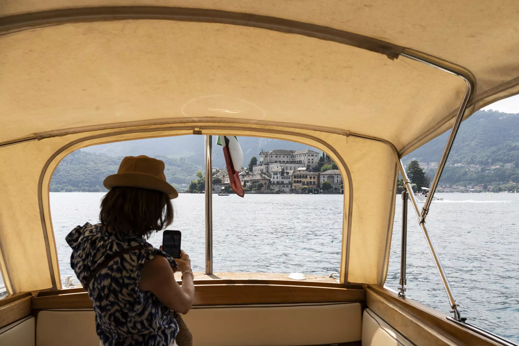 Lake Orta, Piedmont, Italy. A woman takes a photo of the lake from a boat.