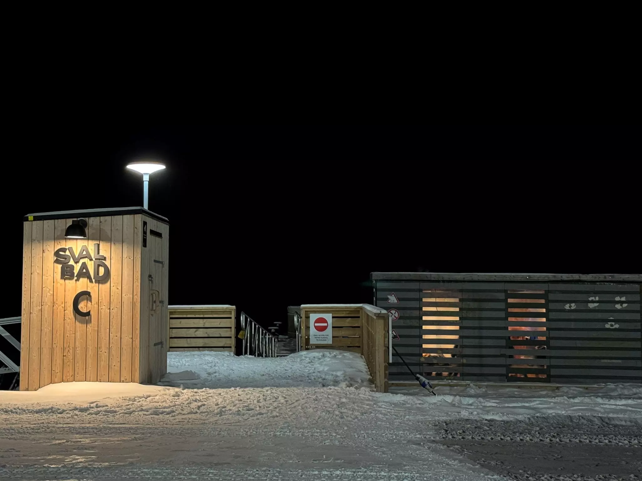 The entrance to a sauna surrounded by snow at night