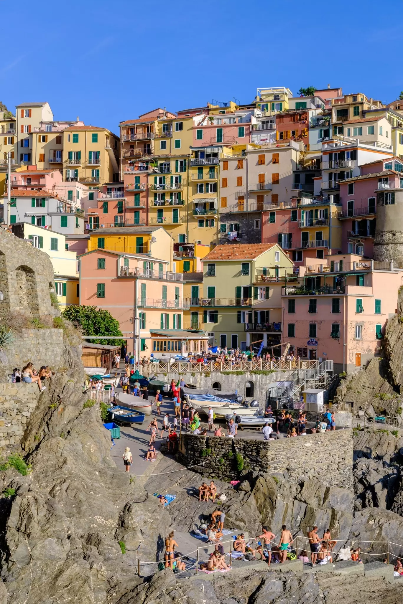 Colorful houses are built into a cliff overlooking the ocean in Italy.